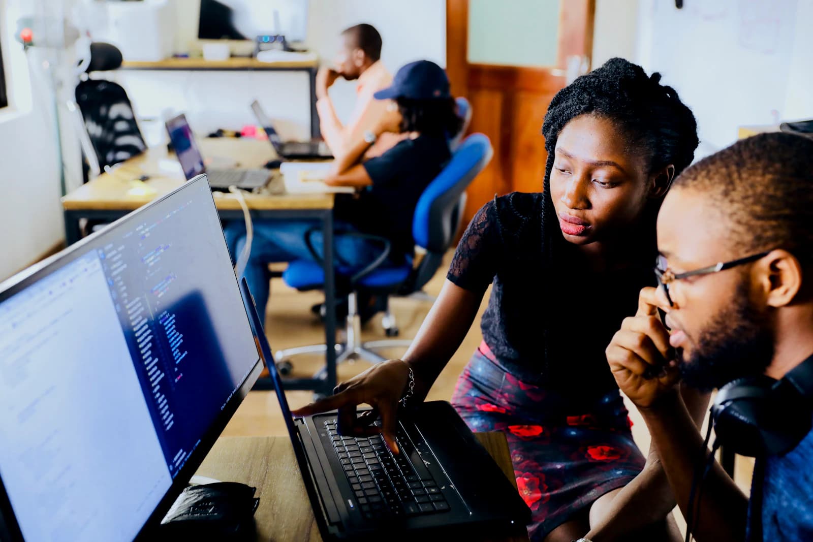 Two developers reviewing code on a laptop